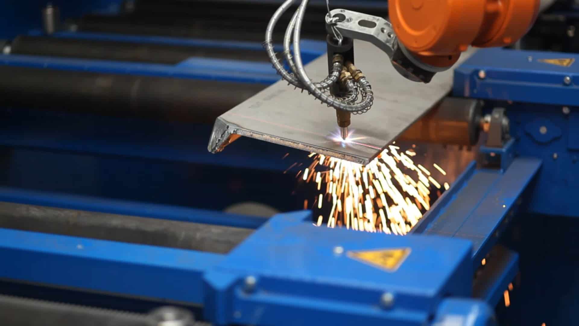 ロボットガス切断トーチが、自動切断システムで鋼板を加工する際に火花を散らしています。