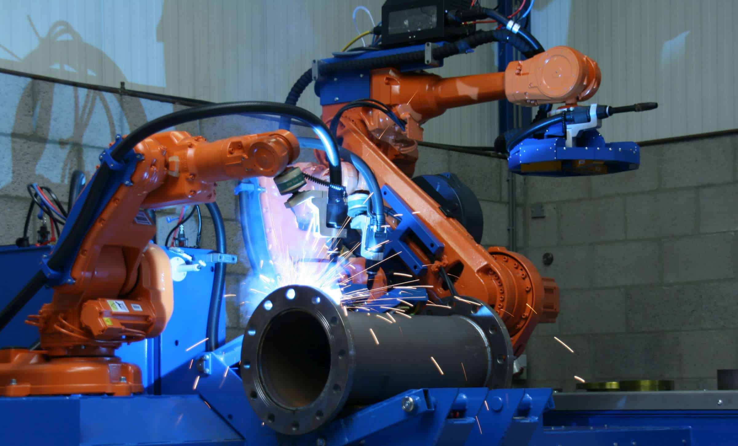 自動フランジ組立ラインでフランジを配管部分に組み付けるロボット溶接システム。